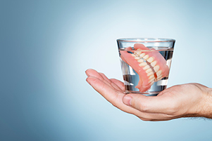 a pair of traditional dentures in a glass of water